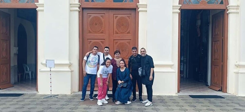 A group of people standing in front of a building with large wooden doors. 1