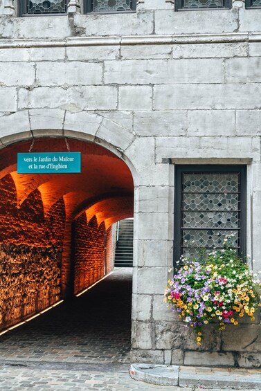 An arched stone structure with a hanging flower basket. 1