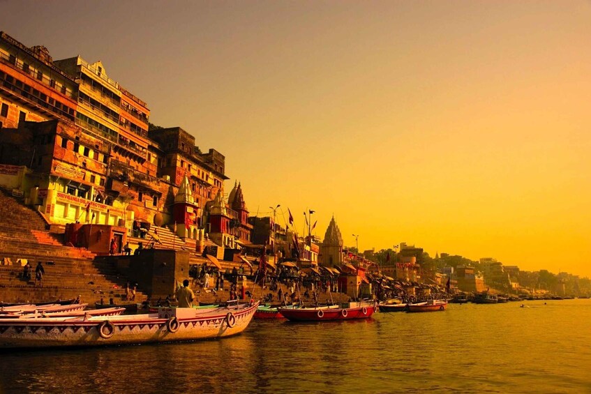 A riverside cityscape with boats docked along the riverbank. 4