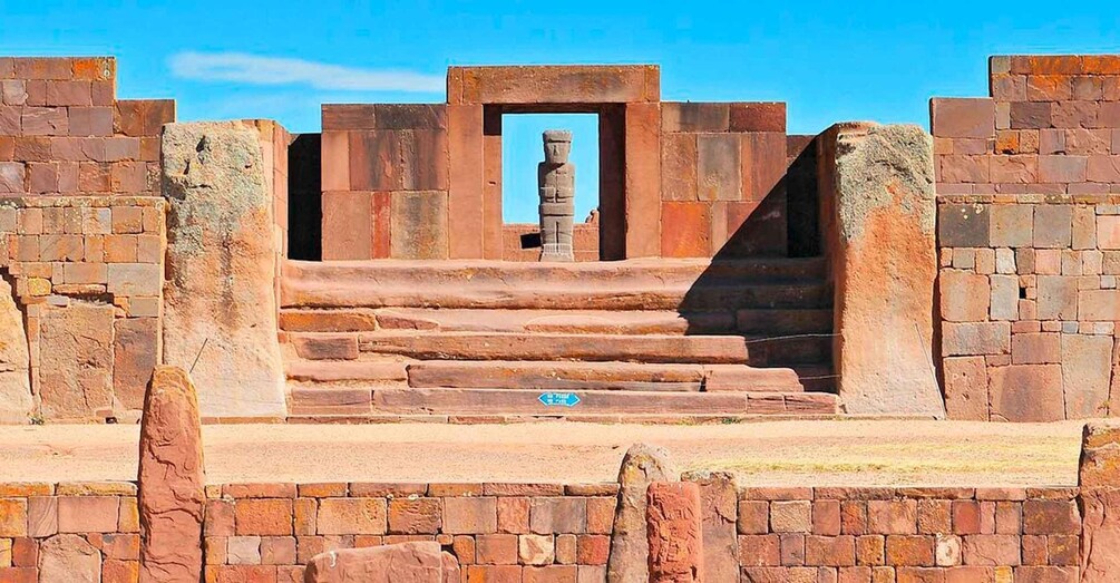 A stone staircase leading to a doorway framed by stone walls, with a clear blue sky above. 5