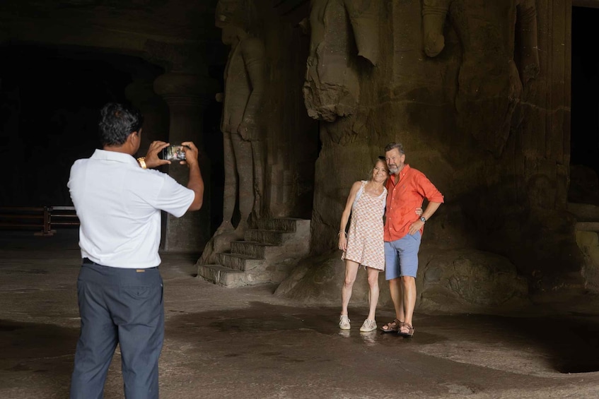 A person taking a photo of a couple in front of a large rock formation. 4