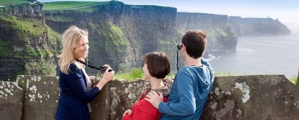 A family of three at a coastal viewpoint overlooking cliffs and the sea. 2