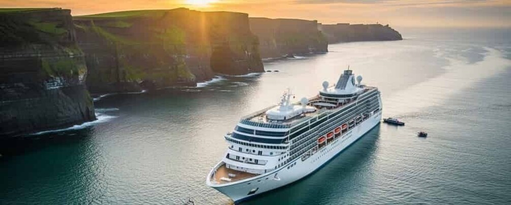 A large cruise ship sailing near cliffs during sunset. 1