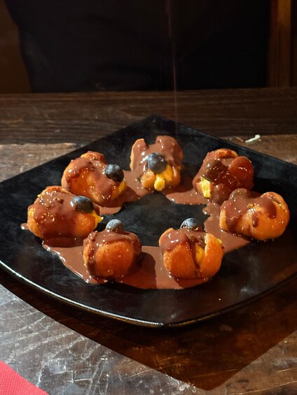 A plate of glazed doughnuts with chocolate chips and syrup. 5