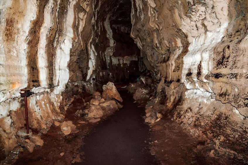 A narrow, rocky cave passage with uneven walls and a dimly lit path. 4
