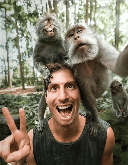 A person with two monkeys on their shoulders in a forest. 1