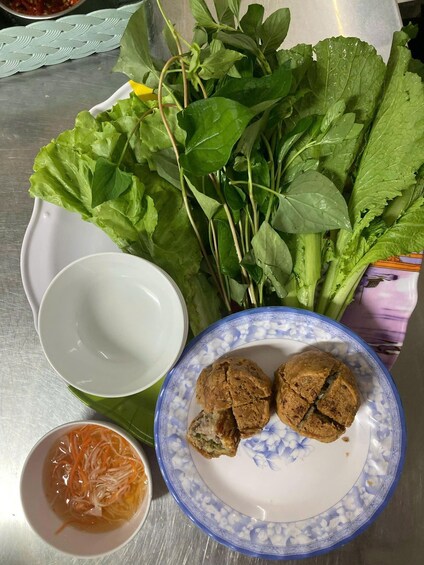 Een tafel met een bord groene bladgroenten, een kom oranjesaus en een bord met twee koekjes. 4