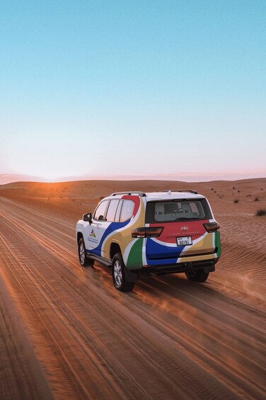 A Toyota Land Cruiser driving on a sandy road in a desert. 2