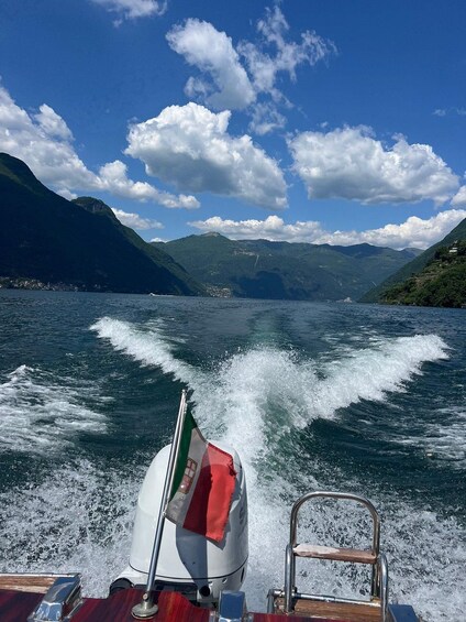 A boat moving through a lake with mountains in the background and a clear sky. 2