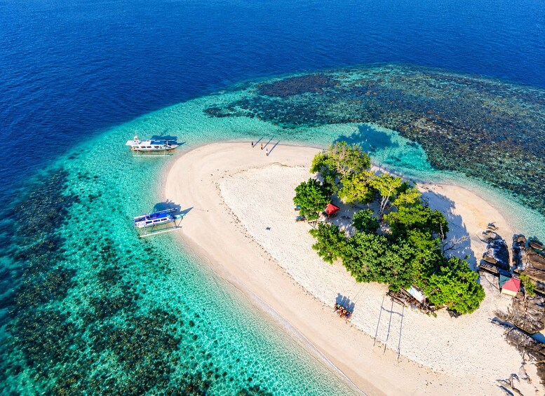 A tropical island with clear turquoise waters, a sandy beach, and a small boat anchored nearby. 1
