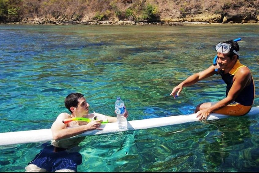 Two people in a clear river, one holding a water bottle and the other sitting on a float. 3