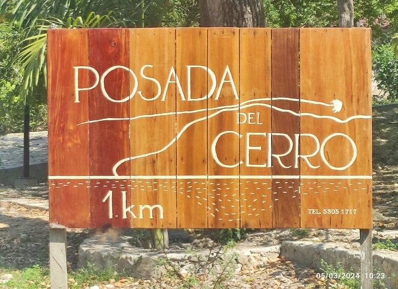 A wooden sign with 'POSADA DEL CERRO' and '1 km' indicating a location 1 km away. 3