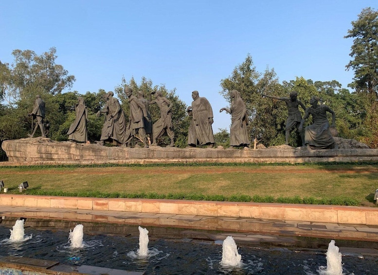 A series of statues on a stone platform with a water fountain in the foreground. 3