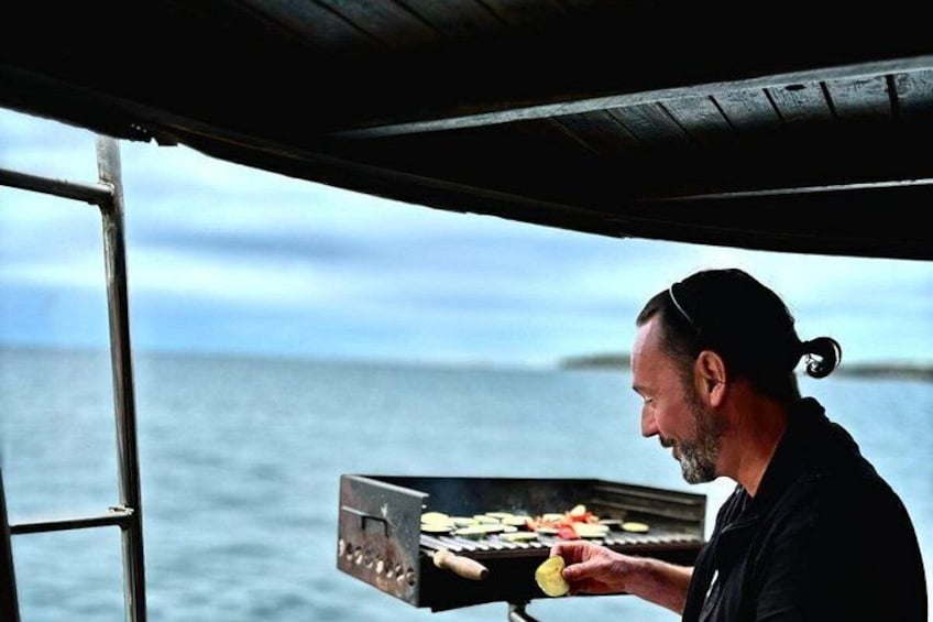 A person grilling food on a boat with the ocean in the background. 2