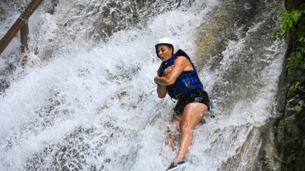 A person in a blue life jacket and helmet navigating a white water rapids. 2