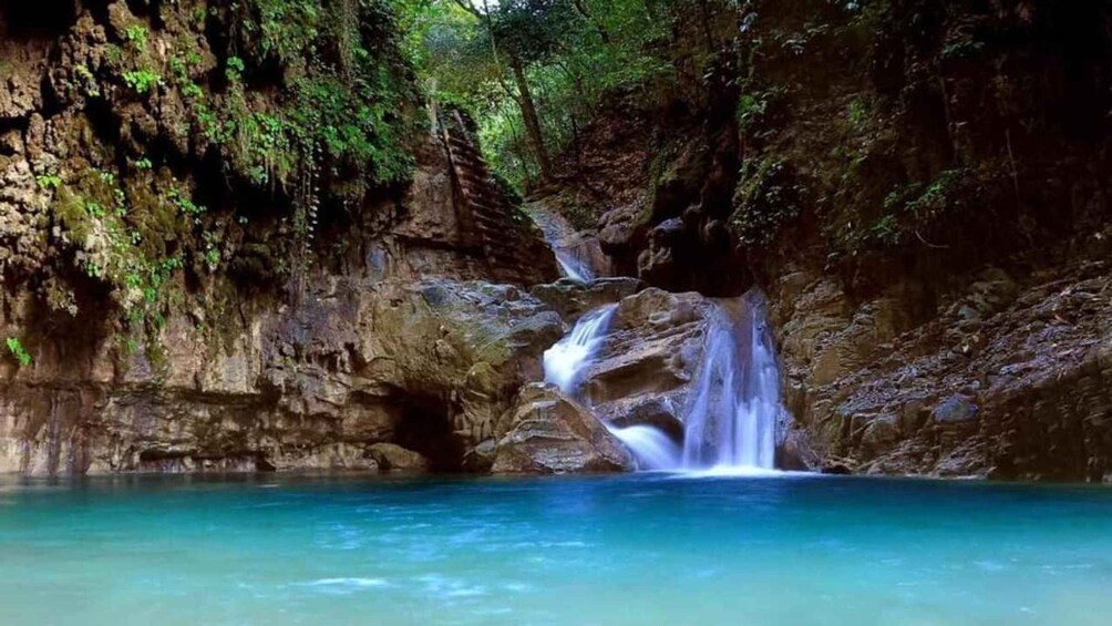 A waterfall in a rocky cave with clear turquoise water. 3