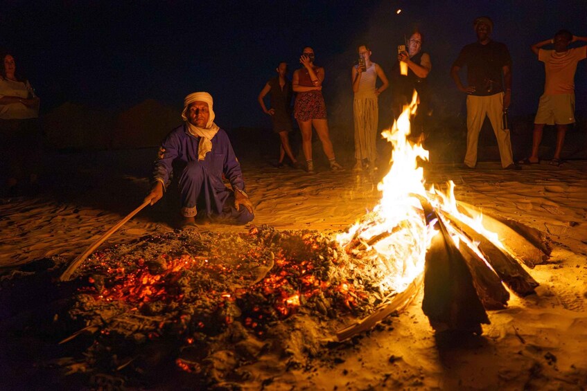 Jemand kocht nachts bei offenem Feuer am sandigen Strand. 1