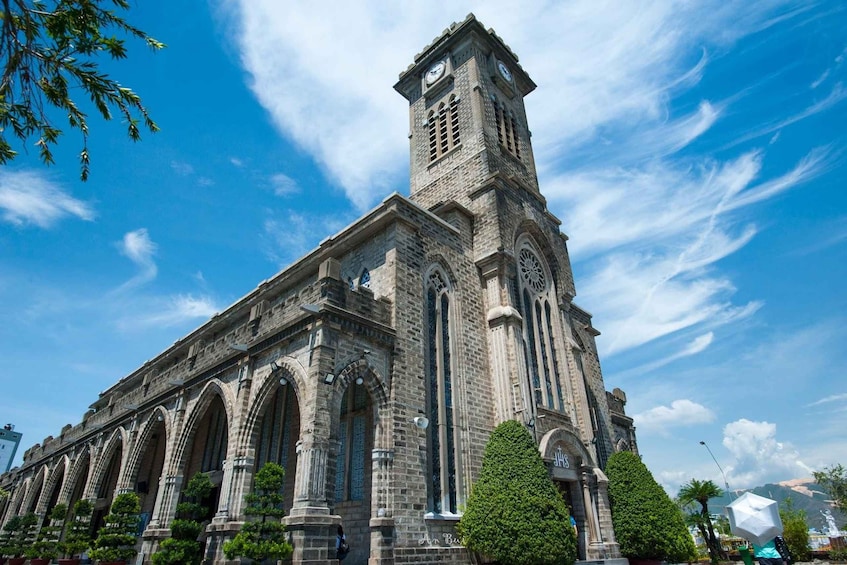 A historic stone church with a clock tower, arched windows, and a clear blue sky. 4