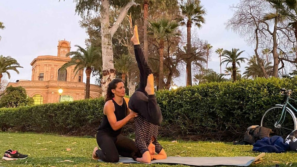 A person performing a yoga pose outdoors with a building in the background. 2