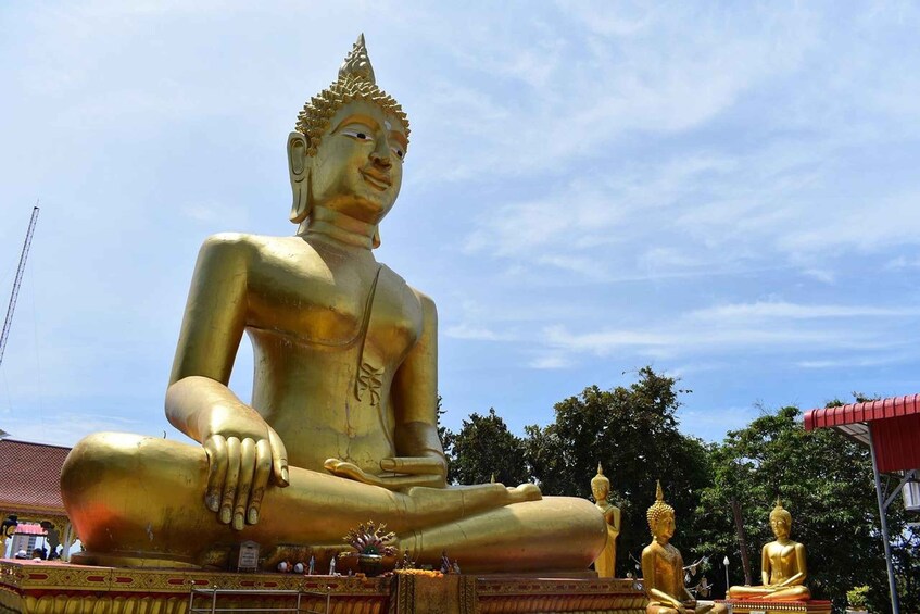 A large golden Buddha statue in a seated position with smaller statues nearby. 2