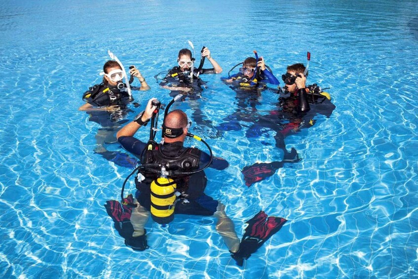 A group of people in a swimming pool wearing scuba diving gear. 3