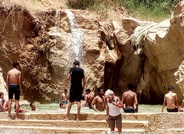 A group of people enjoying a natural hot spring with a waterfall. 4