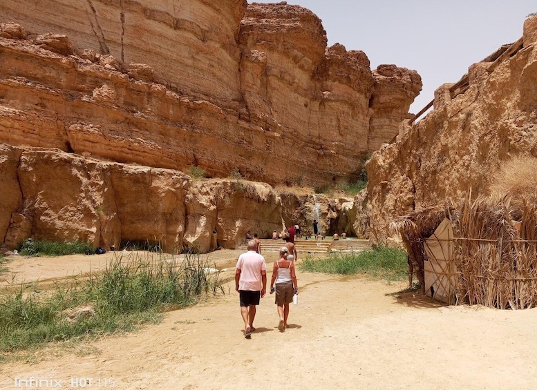 A rocky canyon with people walking along a dirt path. 1