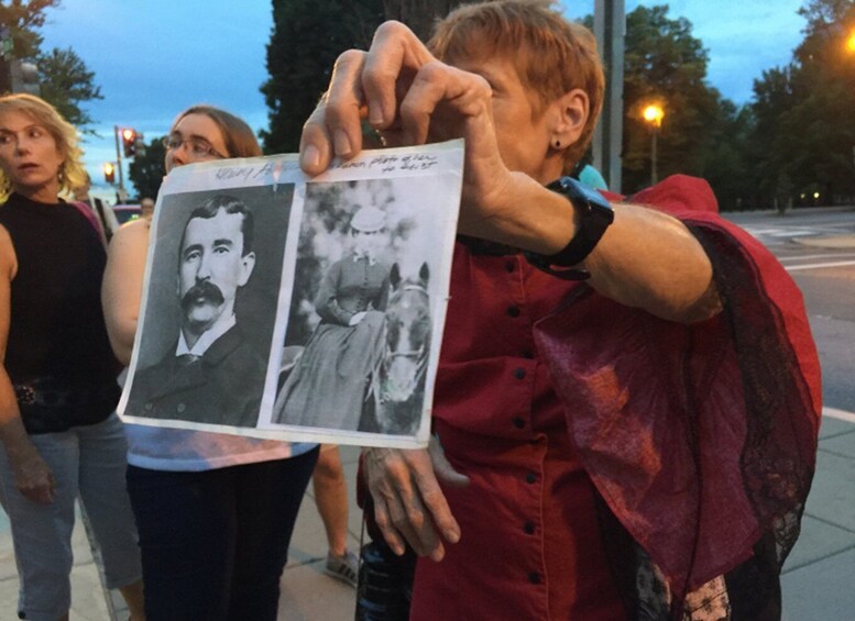 A person holding a photograph of a man and a woman with a horse. 5