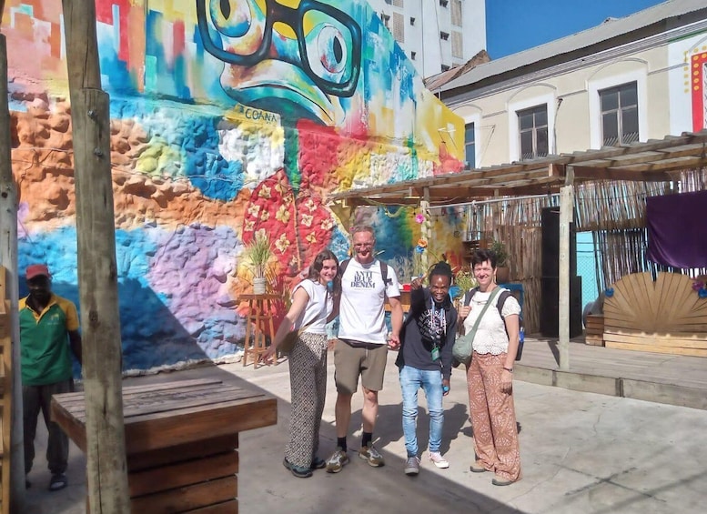 A group of people standing in front of a colorful mural with a large eye design. 4
