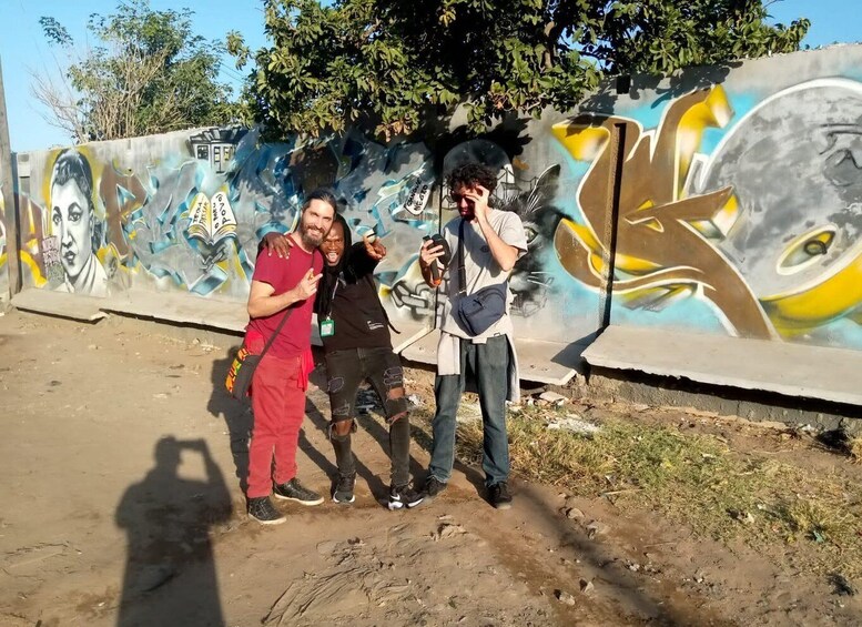Three people posing in front of a colorful graffiti wall. 5
