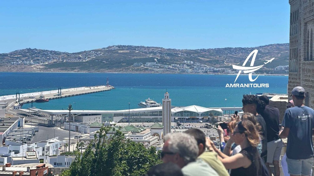 A coastal cityscape with a prominent tower, a pier, and a clear view of the sea. 1