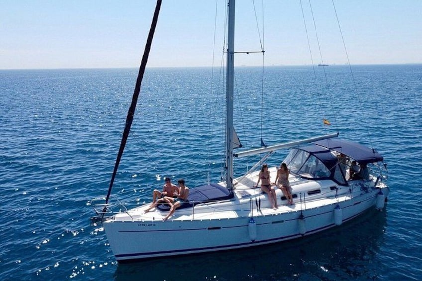 A sailboat with people on board, sailing on a calm sea. 2
