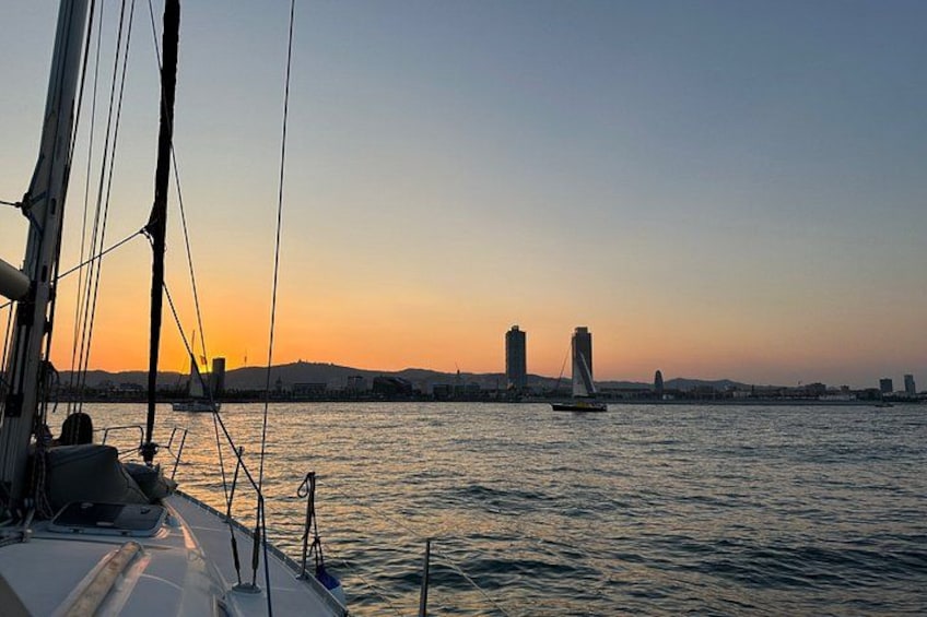 A sailboat on calm waters with a sunset in the background and a bridge in the distance. 4