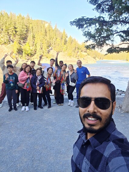 A group of people posing by a river with trees in the background. 5