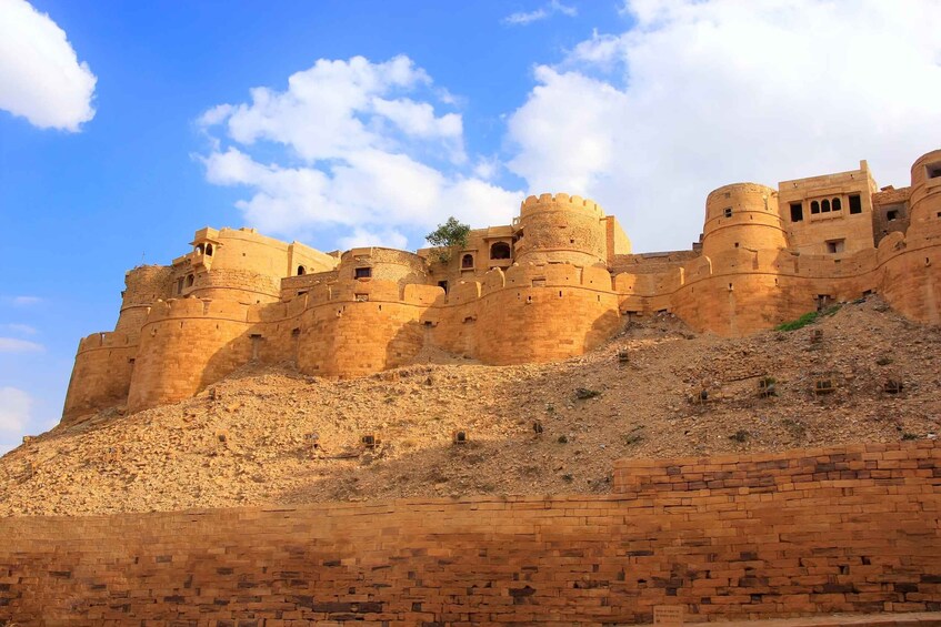 A large, ancient fort with multiple towers and walls, situated on a hill with a clear sky. 3
