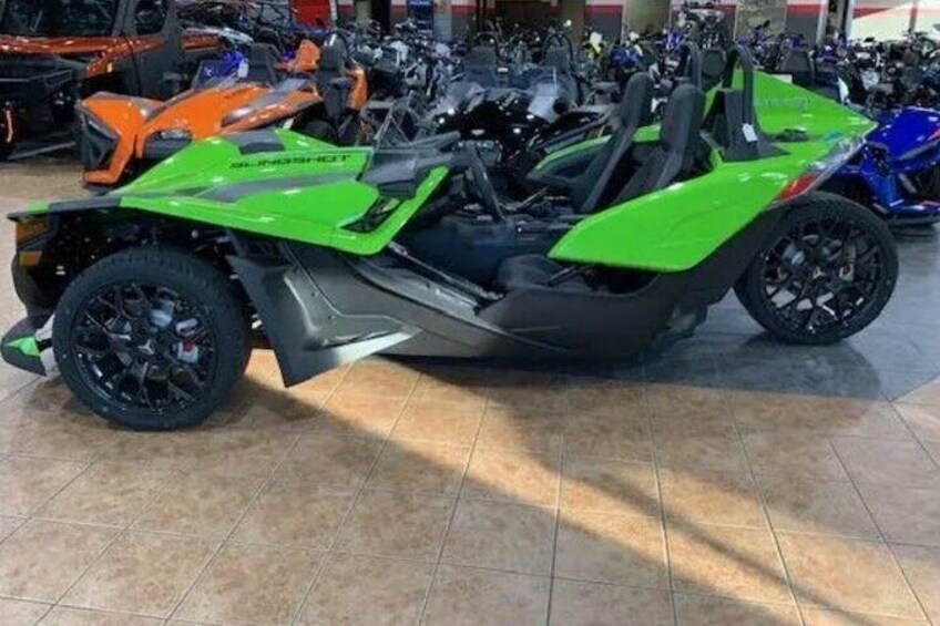 Una motocicletta verde e nera dal design elegante, esposta in una concessionaria insieme ad altri motocicli. 1