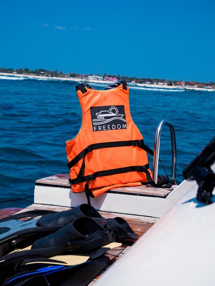 An orange life jacket labeled 'FREEDOM' on a boat. 2
