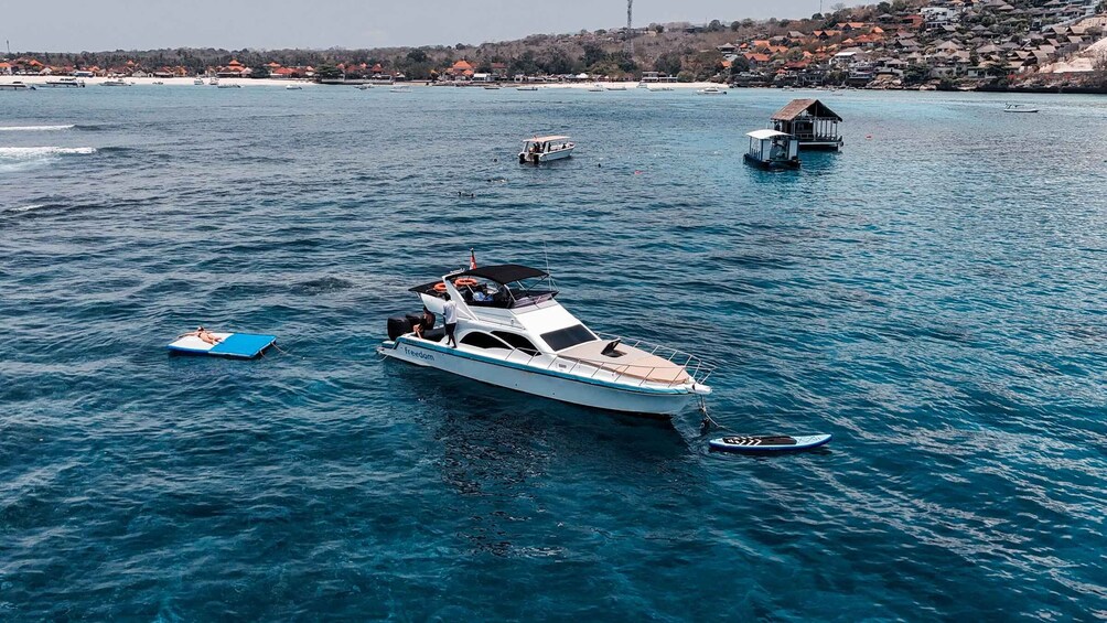 A white yacht named 'Freedom' anchored in a turquoise sea with a small island and houses in the background. 4