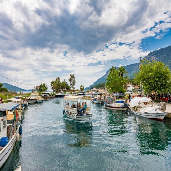 A river with boats docked along the banks, surrounded by greenery and mountains in the background. 2