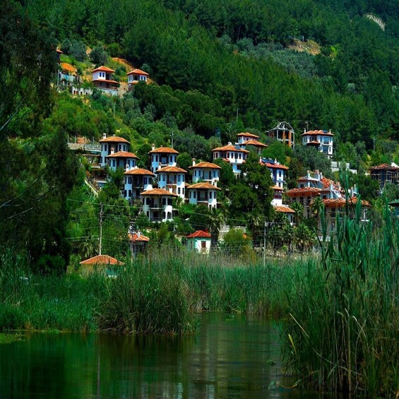A hillside village with terraced houses and a body of water in the foreground. 3