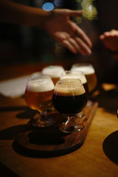A tray with several glasses of beer, some with foam on top. 5