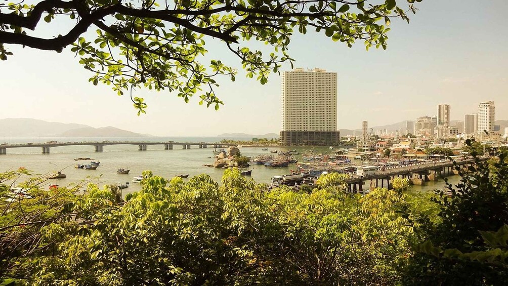 A cityscape with a prominent high-rise building, a river with boats, and a bridge. 2