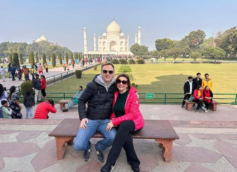 Pariskunta istuu puistonpenkillä, ja taustalla näkyy Taj Mahal. 2