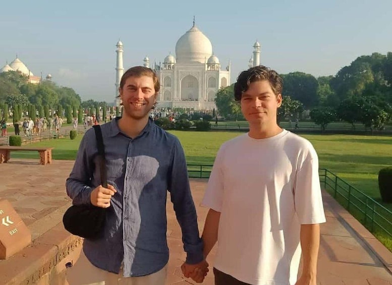 Kaksi ihmistä seisoo Taj Mahalin edessä, taustalla puisto ja puita. 4