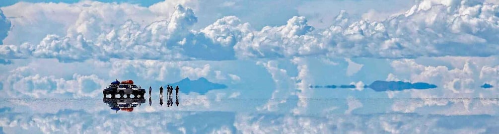 A vehicle with a reflective surface on water, surrounded by people and mountains in the background. 4