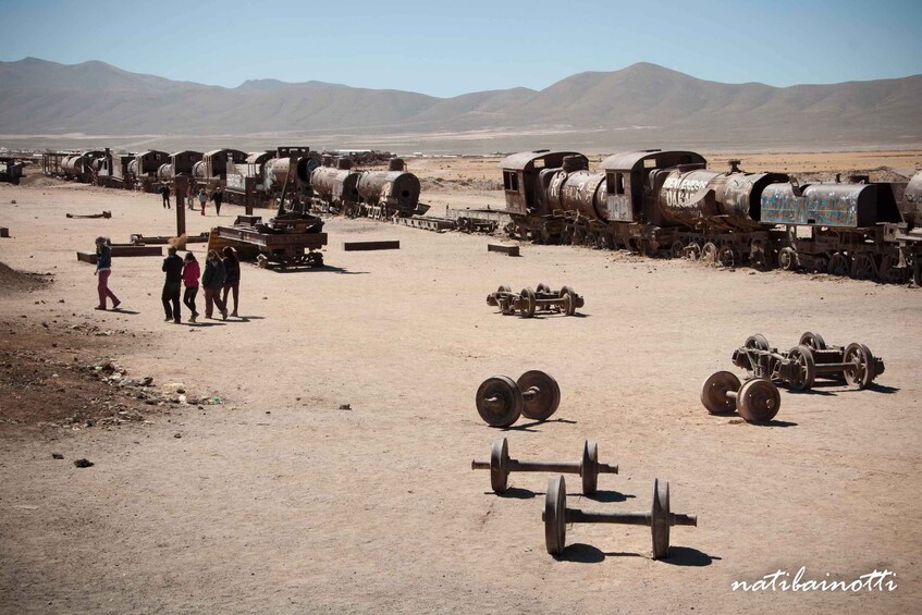 A desert landscape with a row of old, rusted trains and railway tracks. 2