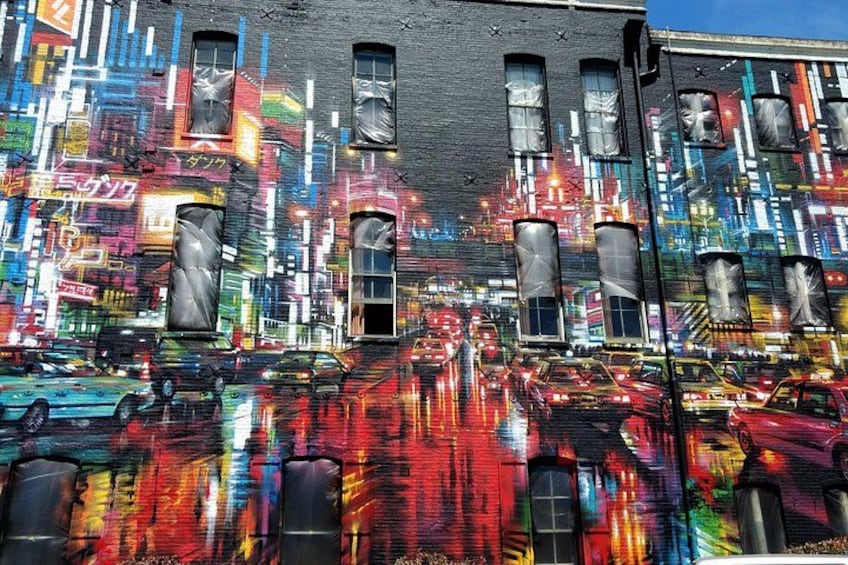 A vibrant street mural with reflections of cars on the wet pavement. 2