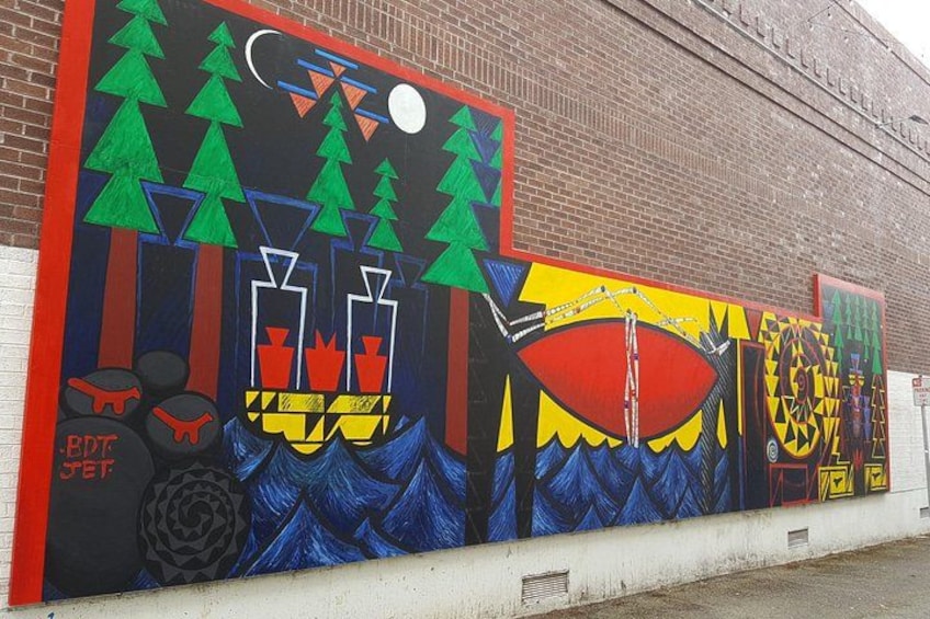 A colorful mural on a brick wall with geometric patterns and abstract shapes. 4