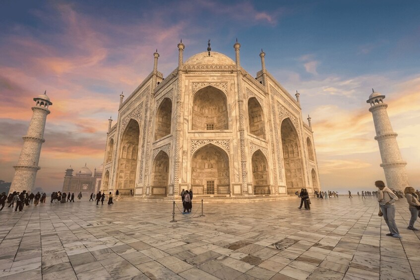 Taj Mahal med sina fyra minareter, ett stort, öppet torg och människor som promenerar runt omkring. 1