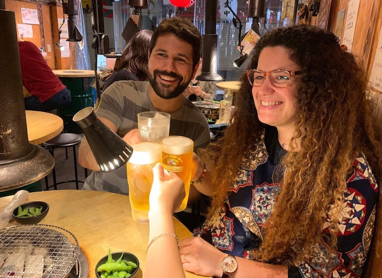 Two people toasting with beer glasses at a restaurant. 1